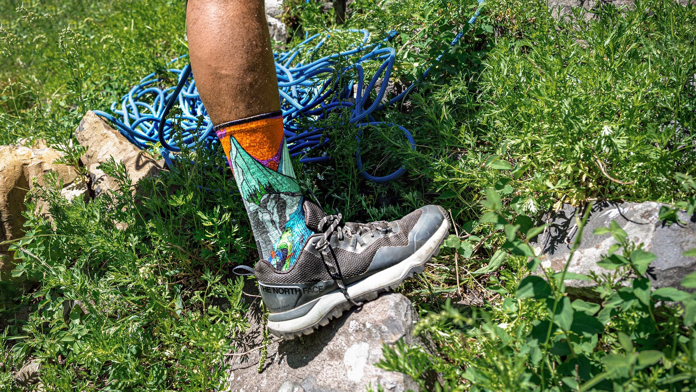 Close up of a person wearing socks while hiking to the base of a rock climb