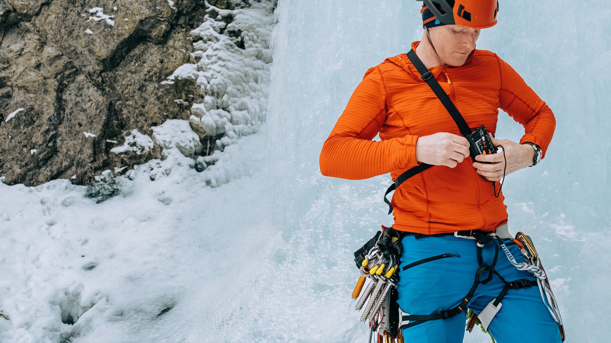 An ice climber turns on an avalanche transceiver before climbing a frozen waterfall