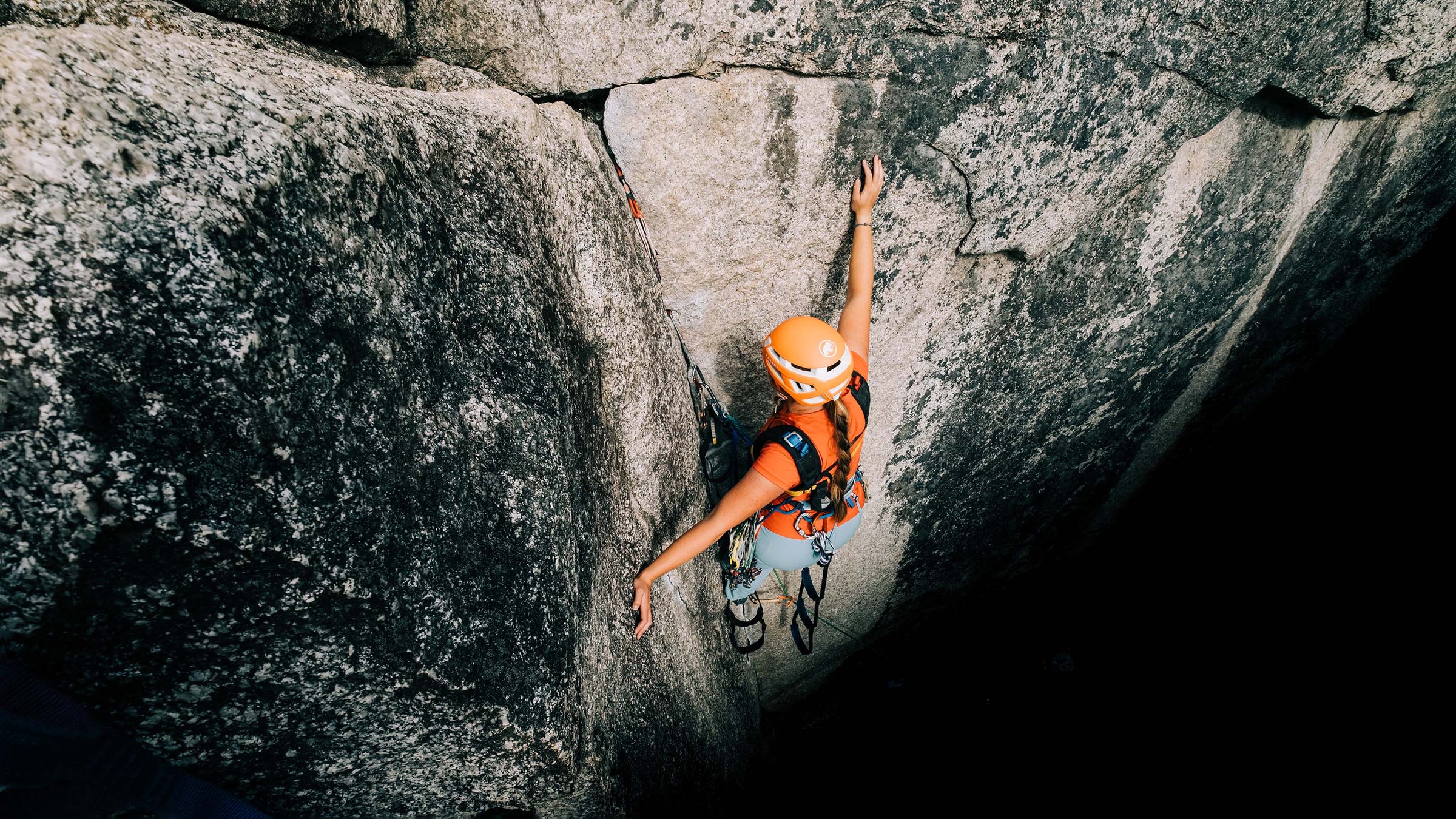 A woman aid climbs a rock face while rock climbing