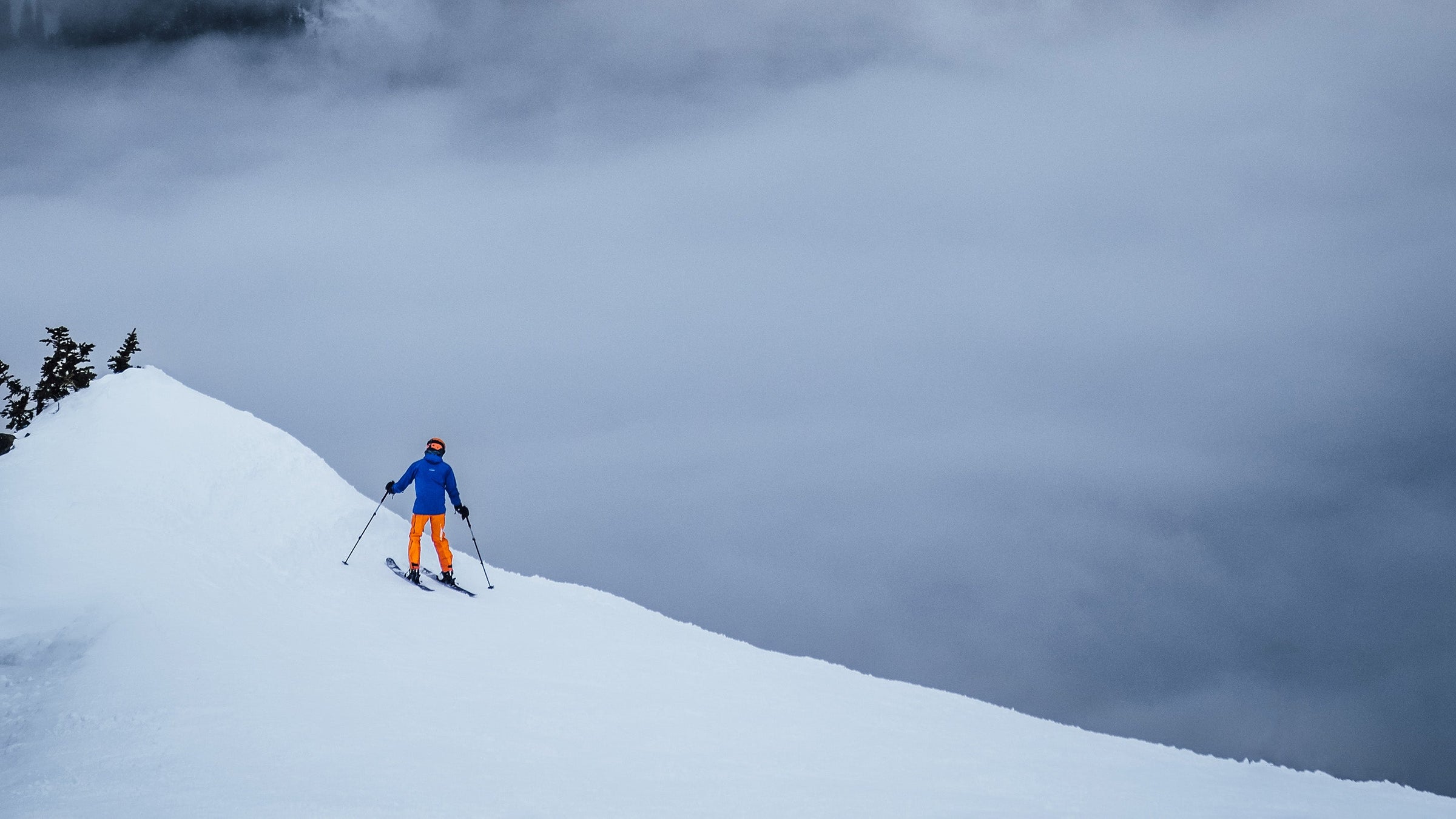 A skier descends a mountainside into the clouds