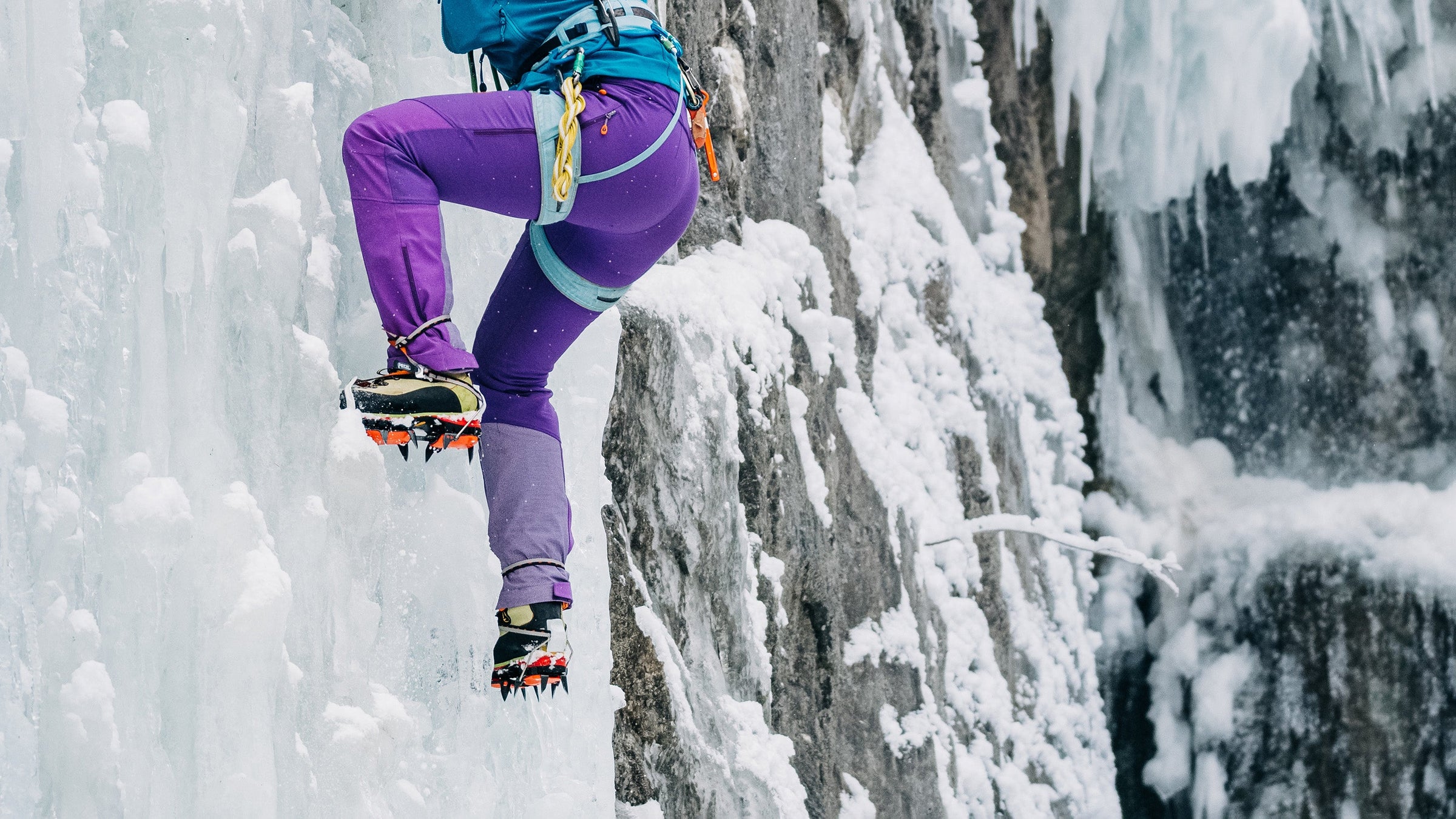Close up of a female ice climber kicking her crampons into the ice of a frozen waterfall