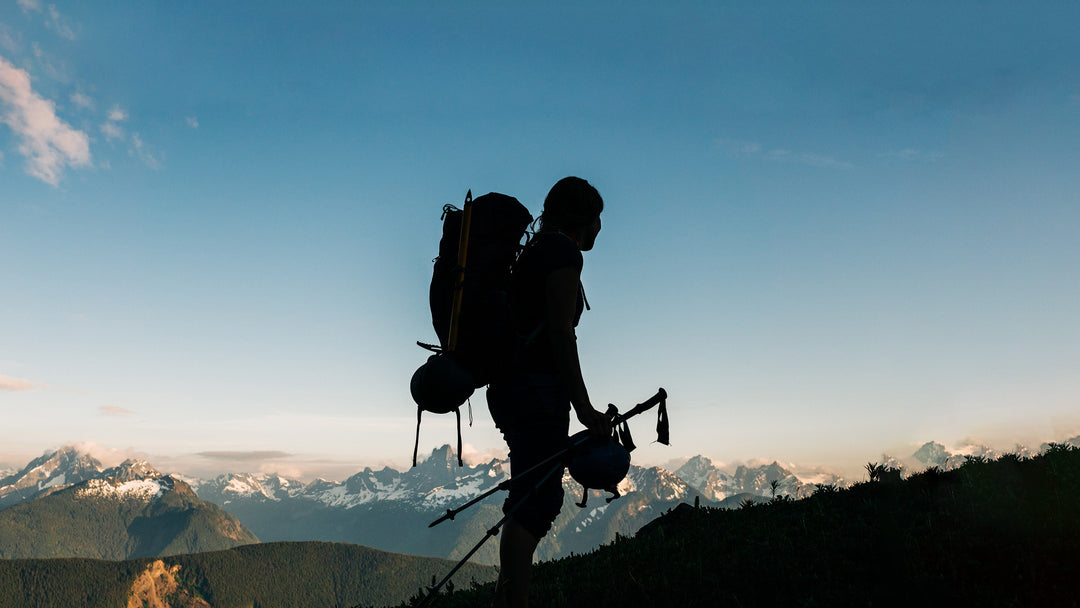 Silhouette of a female backpacker who is hiking in a scenic alpine meadow 