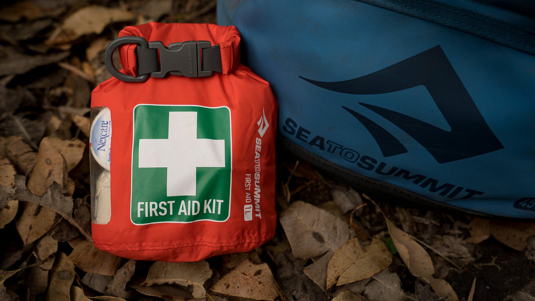 Wilderness first aid kit propped up against a backpack in the backcountry