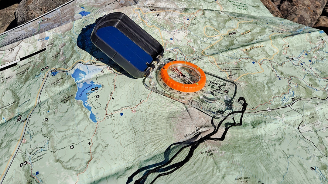 A compass sits on a topographical map in the backountry