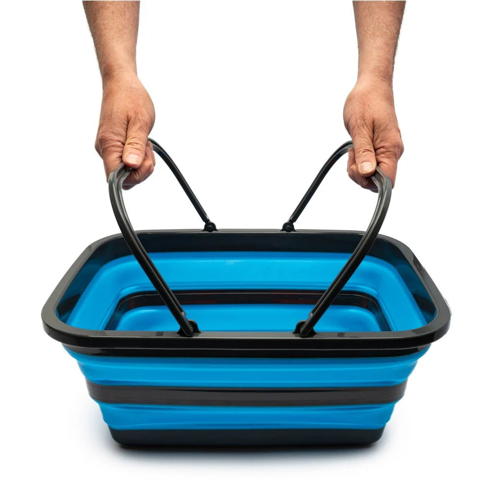 Blue and black collapsible basket held by two hands on a white background