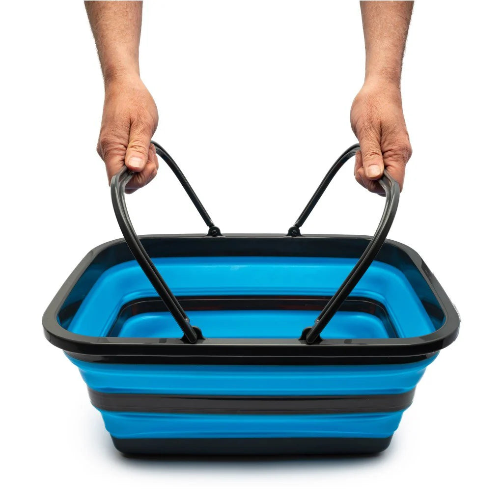 Blue and black collapsible basket held by two hands on a white background