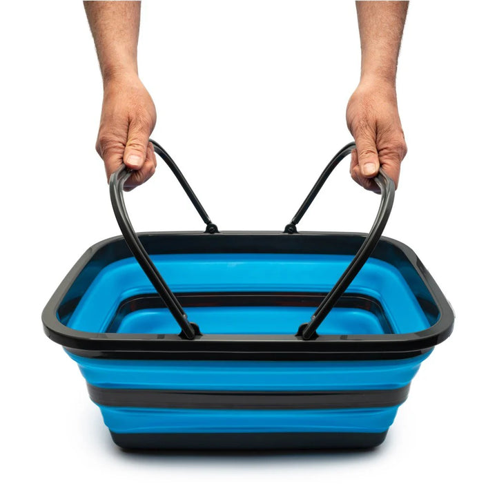 Blue and black collapsible basket held by two hands on a white background